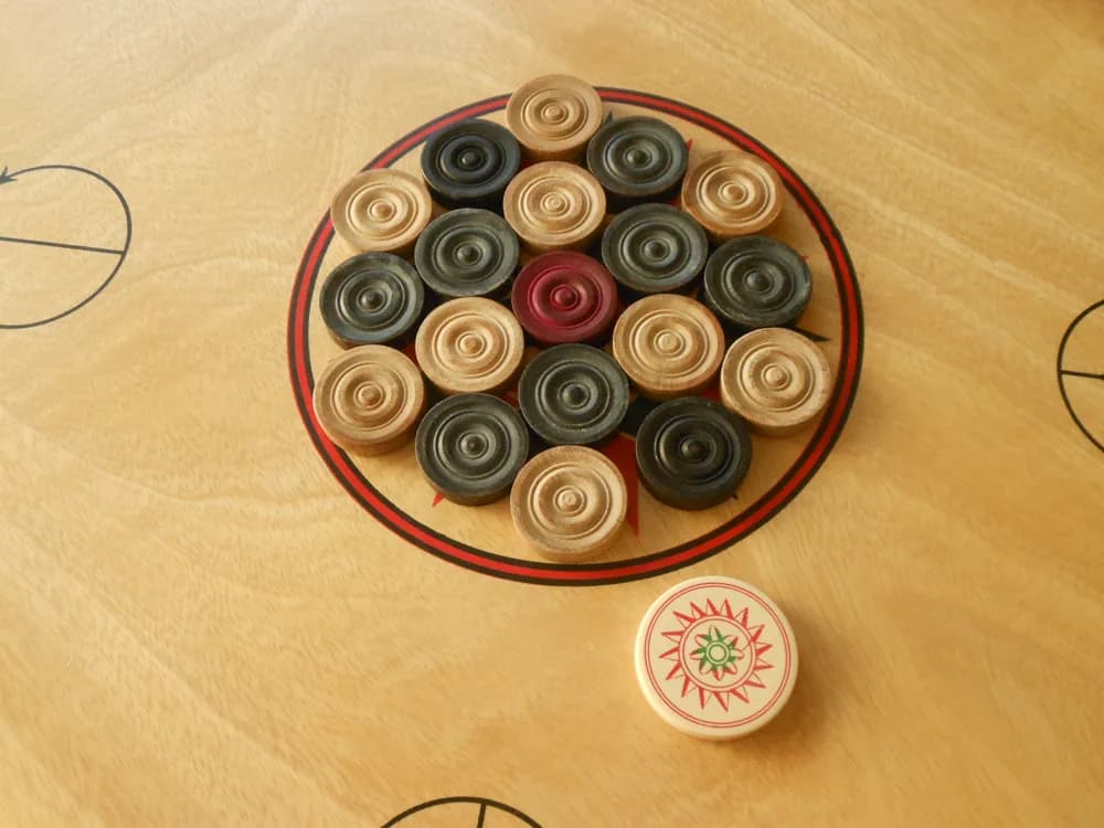 Carrom board set up with black and white pieces
