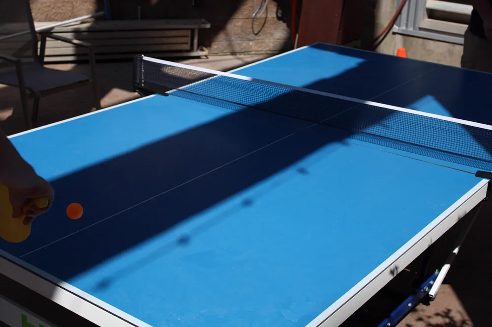 Blue table tennis table with net and paddles